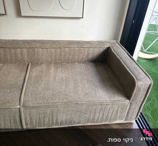 ספת בד מרופדת ונקייה בסלון בית עם רצפת פרקט